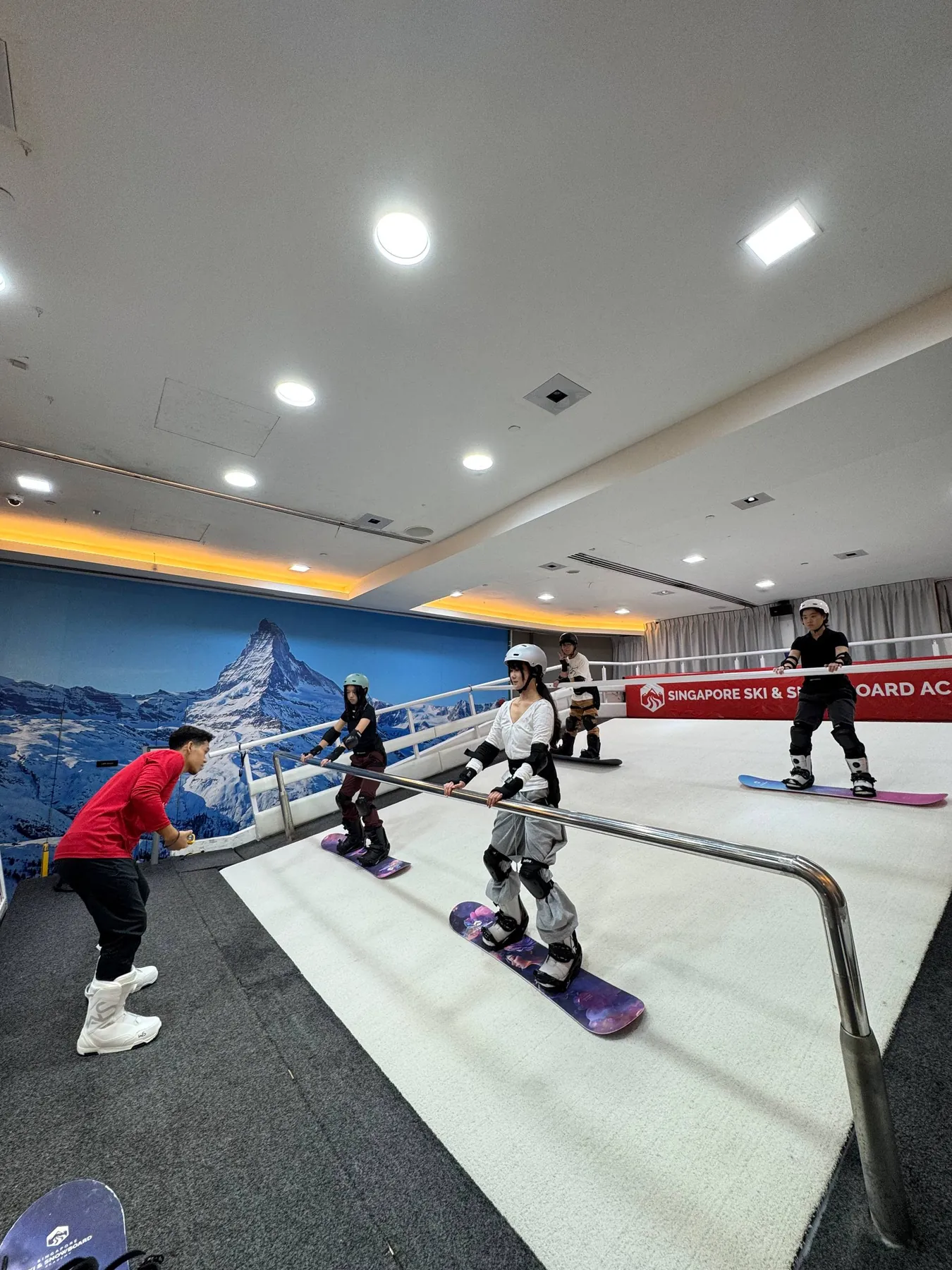 Members practising snowboard technique with coaching on an indoor simulator